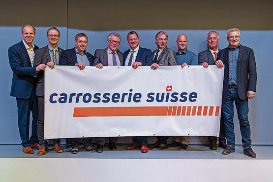 Ensemble pour l’avenir: le président central Felix Wyss (au centre), le président de l’AIRC, Erik Papinski (4e à partir de la gauche), et les membres de la direction générale avec le nouveau logo de la Fédération suisse de la Carrosserie.	Photo: dr