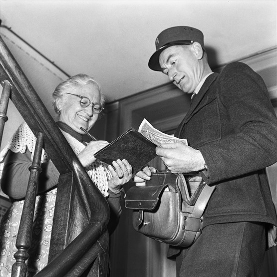 Da war die AHV-Welt noch in Ordnung: Ein Briefträger zahlt einer Rentnerin die AHV-Prämie aus. Das Bild stammt aus dem Jahr 1955.Bild: Keystone