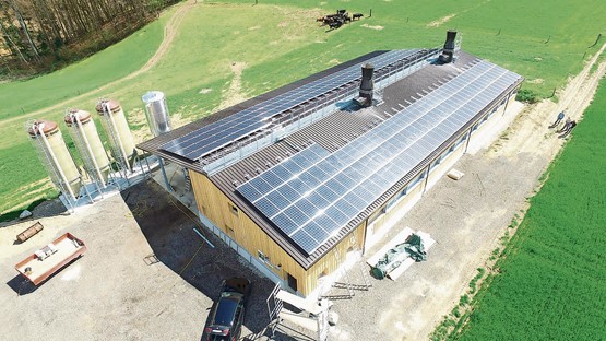 Geflügelstall in Hellsau BE: Zwischen den Modulen der Fotovoltaikanlage (70 kWp) sind die beiden Rohrbündelwärmetauscher zu sehen, links hinter dem Gebäude drei Futtersilos und der Wärmespeicher. Für die Wärmepumpe wurden rund um das Stallgebäude 2800 Meter Soleleitungen im Erdboden verlegt.Bilder: zVg