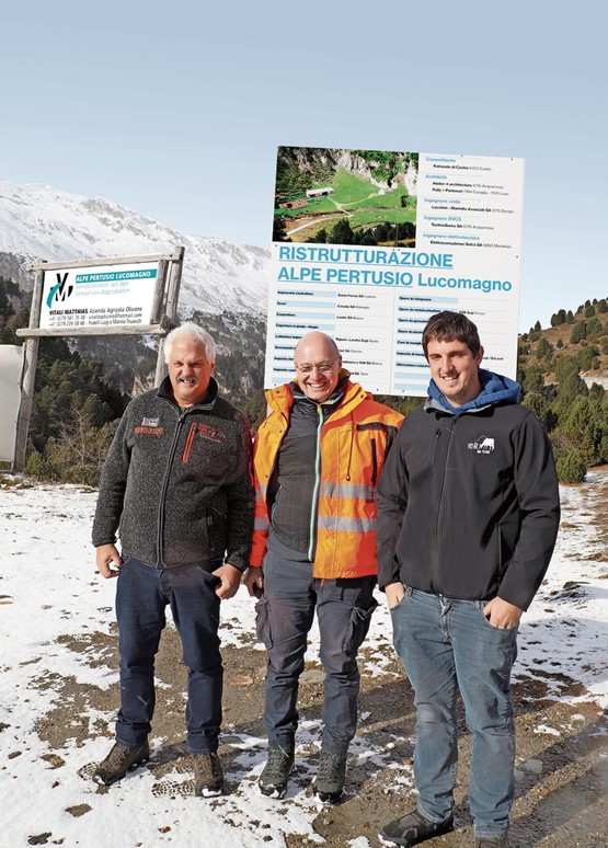 Doriano Vitali, Giorgio Bassi und Matthias Vitali (v.l.) stehen vor dem Bauschild der Alpe Pertusio. 