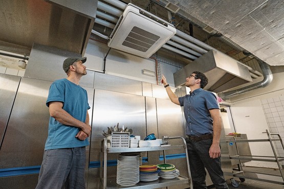 Nik von Frankenberg, beim Basler Foodcourt «Klara» unter anderem für Infrastruktur und Maintenance zuständig, lässt sich von PEIK-Energieberater Sandro Onorati die Optimierung der Lüftung erklären. Bilder: zVg/Martin Bichsel/EnergieSchweiz