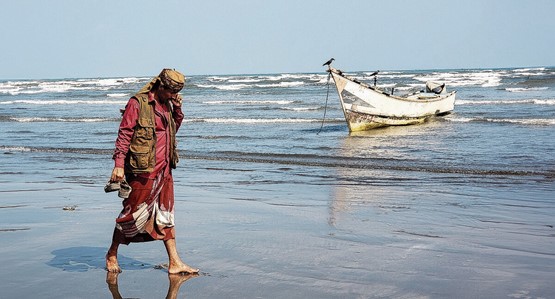 Un homme passe devant un bateau ancré sur la plage près du détroit de Bab al-Mandab (Aden) au Yémen.Photo: Keystone