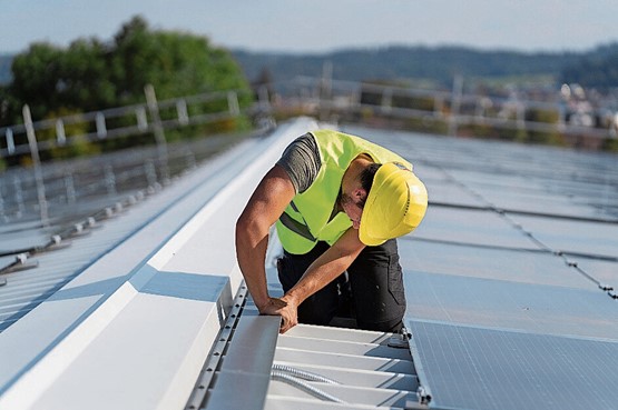 Le métier d’installateur solaire est nouveau: celui-ci monte notamment des installations solaires sur les toits.Photo: Keystone