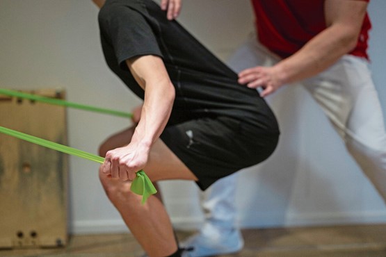 Die Prämien-Entlastungs-Initiative ist in Tat und Wahrheit eine Kostensteigerungs-Initiative. Eine Physiotherapeut kontrolliert die Bewegungen eines Patienten während einer Übung mit dem Theraband.Bild: Keystone