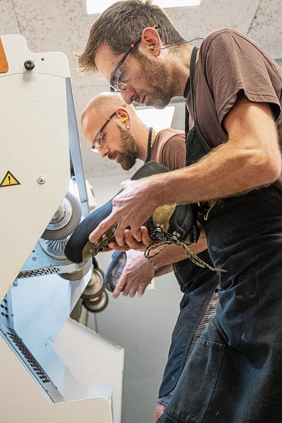 Bevor eine neue Sohle an die Bergschuhe geleimt werden kann, müssen die Mitarbeiter von New Rada die alten Gummi- und Kunststoffreste komplett abschleifen.