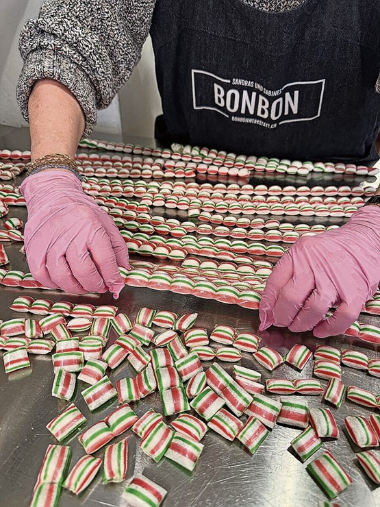 Die abgekühlten Zuckerstangen werden, indem sie über die Kante gebrochen werden, zu Kissenbonbons.. 